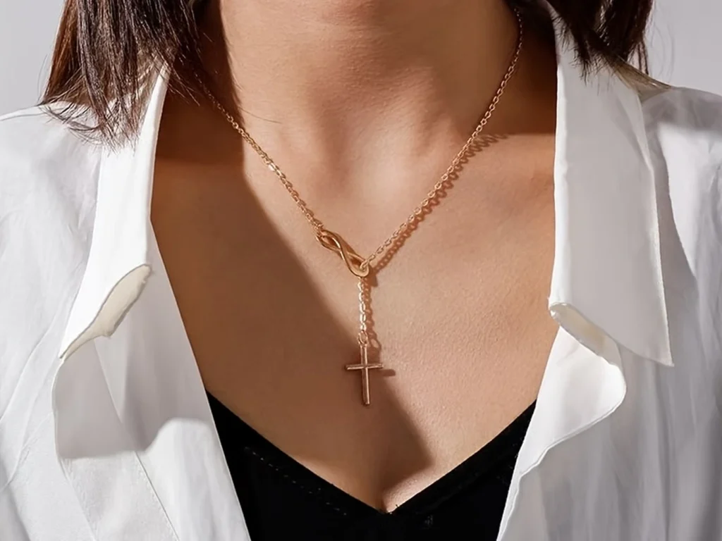 Gold-tone infinity cross necklace worn on a model
