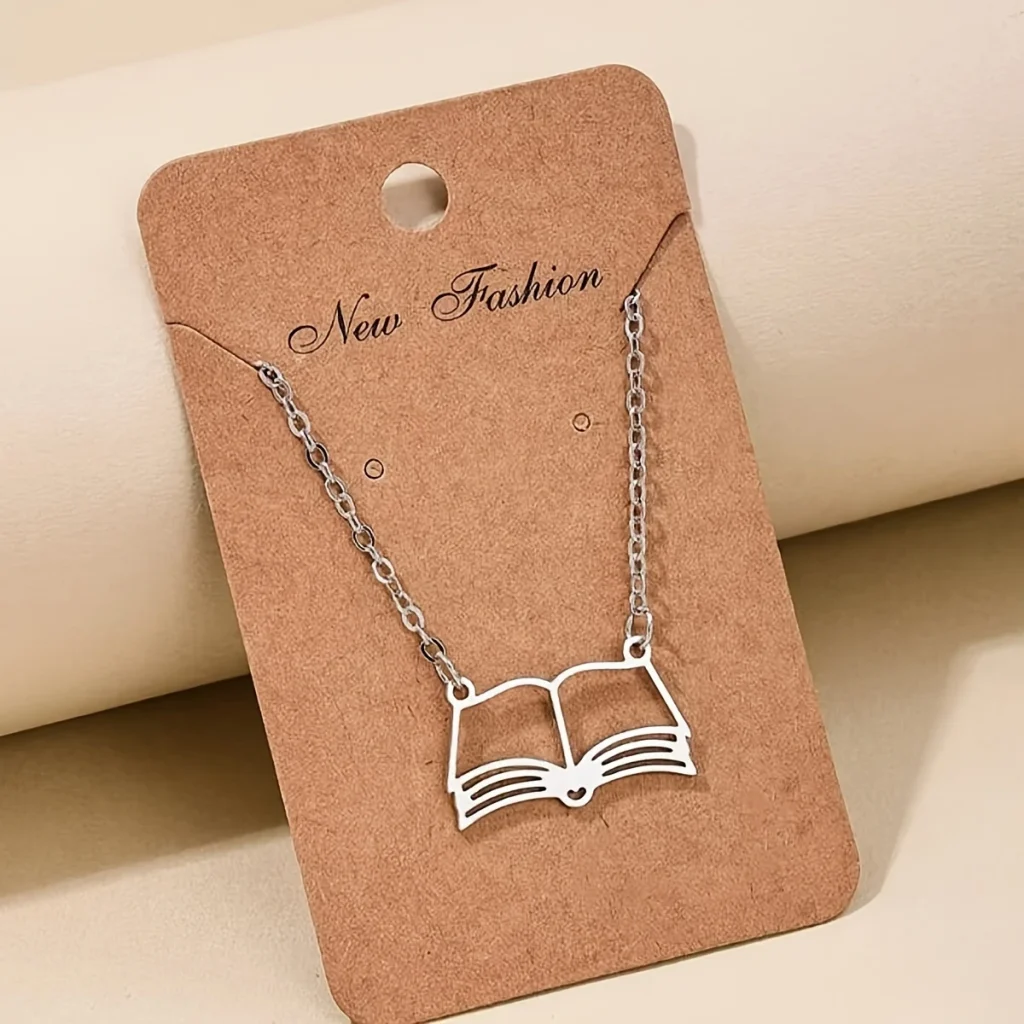 Silver-tone open book pendant necklace on display card