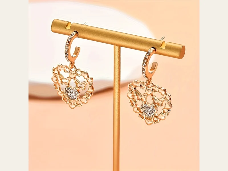 Gold-tone heart-shaped hoop earrings displayed on a stand