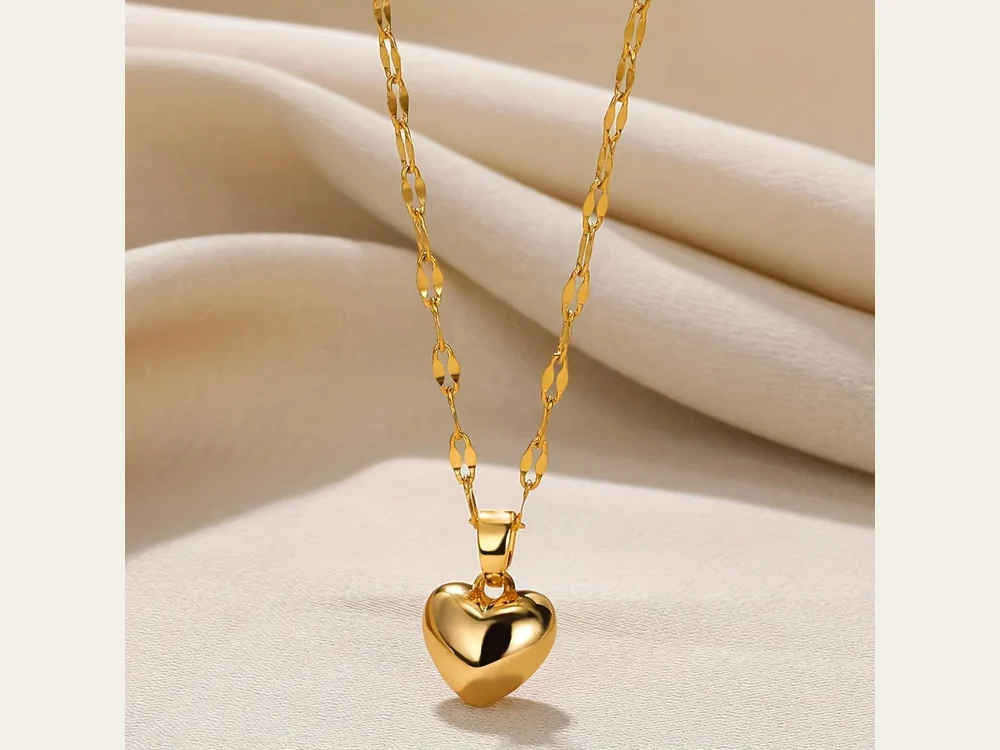 Gold-tone heart pendant on a linked necklace against pale fabric